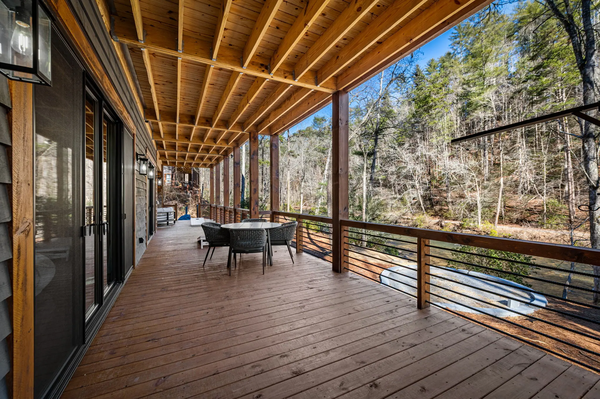 Lower level balcony with a stylish wood railing and surrounding forest views.