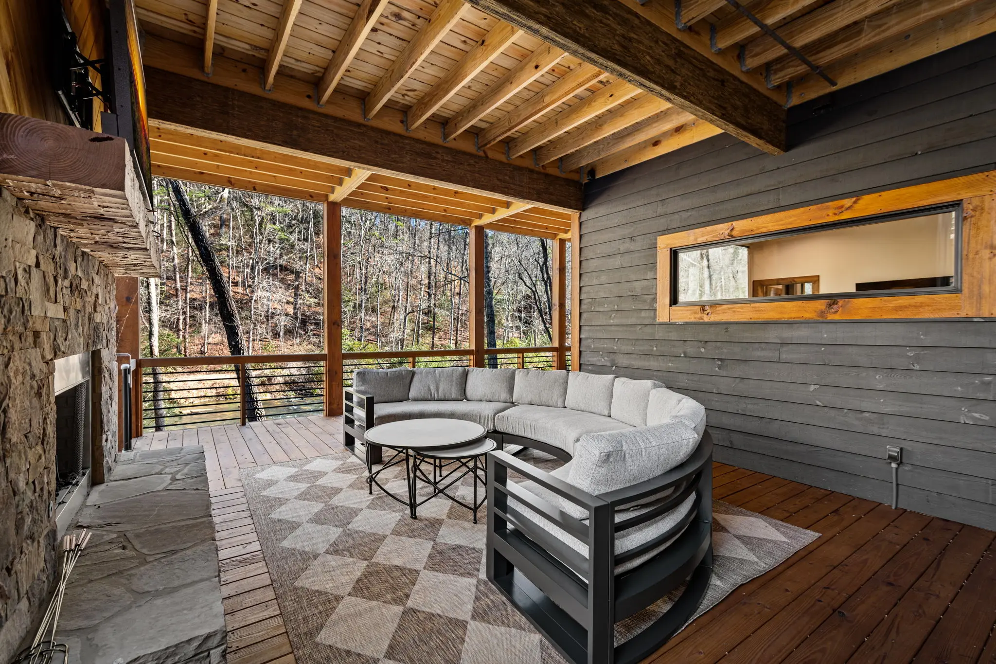 Balcony seating area on the lower level with wood tones and nature views.